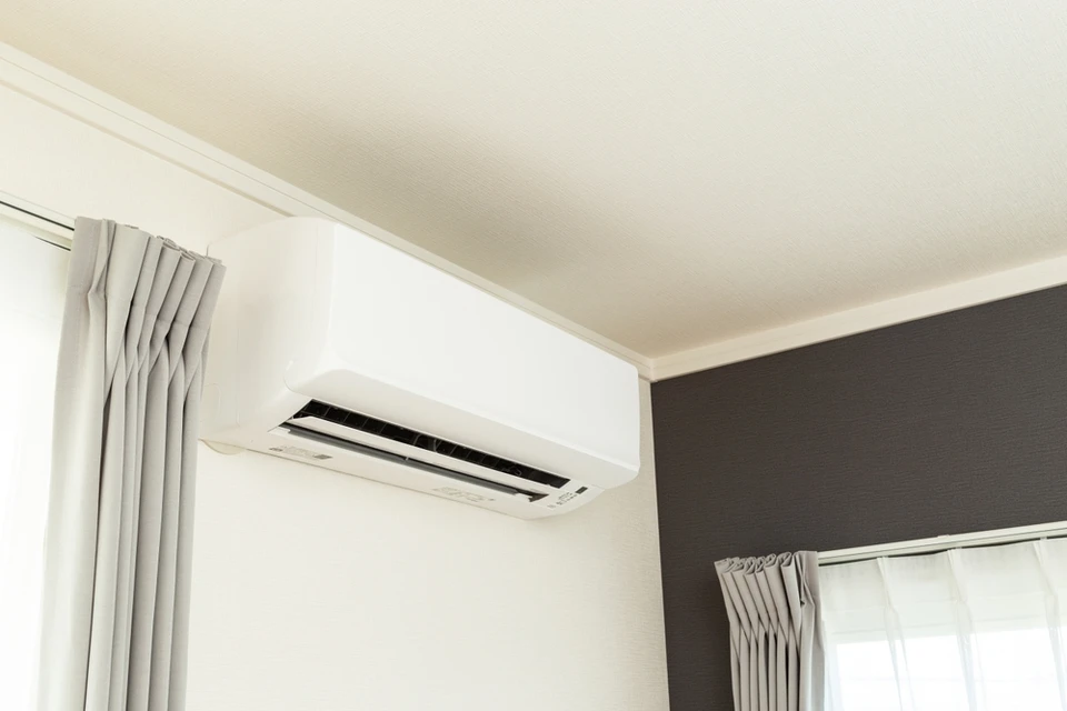 Int&eacute;rieur r&eacute;sidentiel moderne avec climatiseur split mural blanc install&eacute; au plafond pr&egrave;s d'une fen&ecirc;tre
