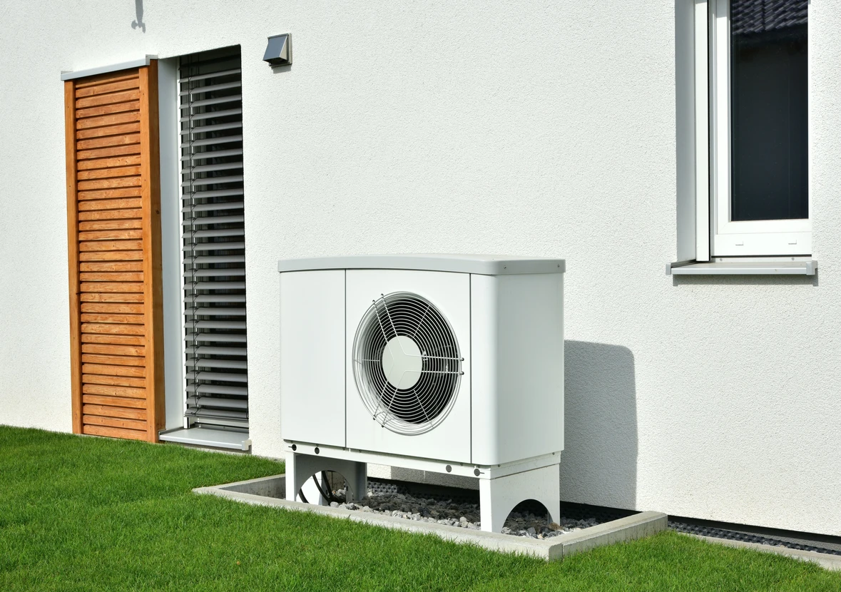 Extérieur résidentiel moderne avec pompe à chaleur air-eau installée sur socle béton contre façade blanche