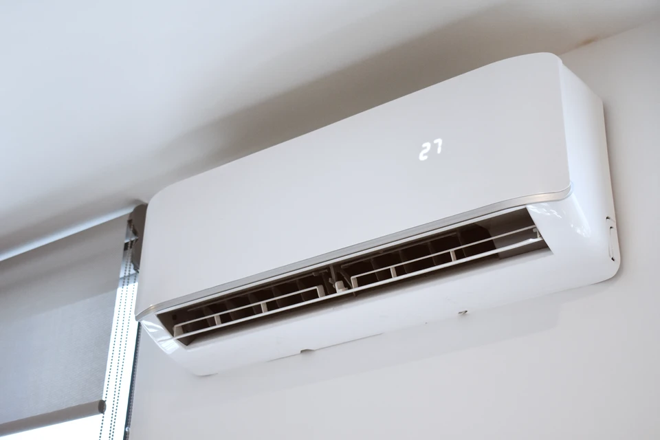 Intérieur résidentiel moderne avec climatiseur split mural blanc installé au plafond près d'une fenêtre
