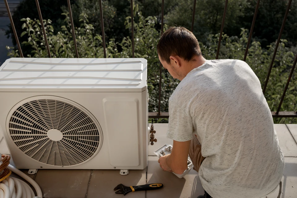 Extérieur résidentiel moderne avec pompe à chaleur air-eau installée sur socle béton contre façade blanche